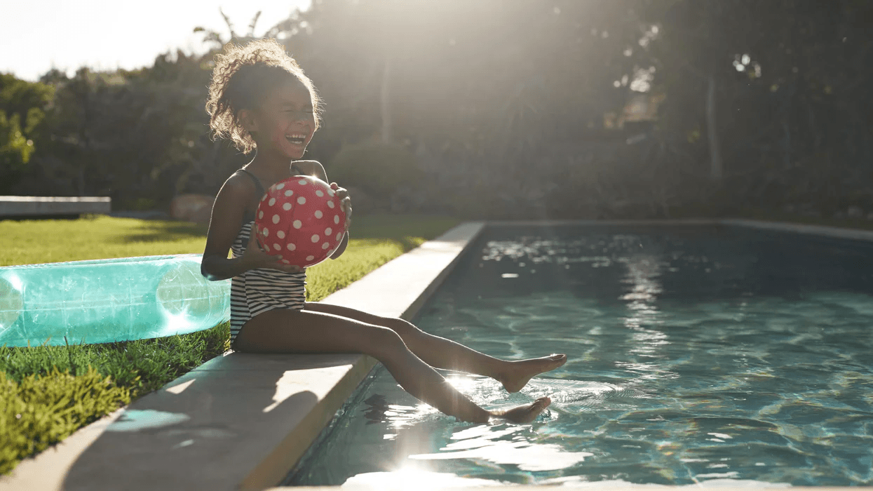 12 super fun (and safe) swimming pool games to try this summer young girl laughing on the edge of a pool- swimming pool games