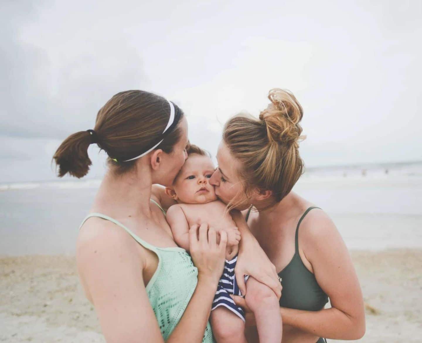 Infant swimming resource lessons could save your baby’s life two women kissing a baby on the cheek on the beach