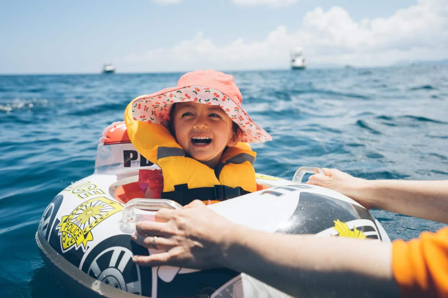 6 best infant life jackets for babies and toddlers little girl smiling on a raft in the ocean