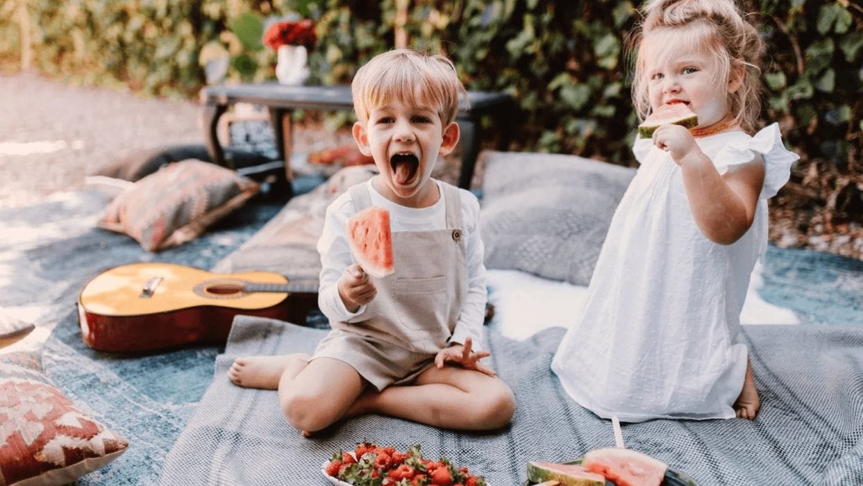 Delicious & kid-friendly recipes for the 4th of July weekend kids eating watermelon on a picnic blanket