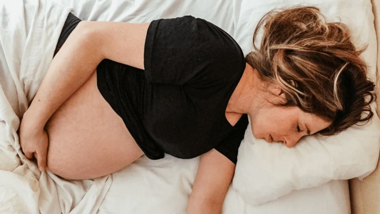 5 tips to combat pregnancy fatigue pregnant woman sleeping while holding belly