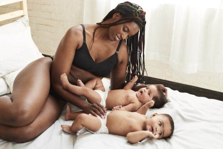 13 best nursing bras that are comfortable & stylish Mom wearing nursing bra and playing with her twins on a bed - best stylish nursing bras
