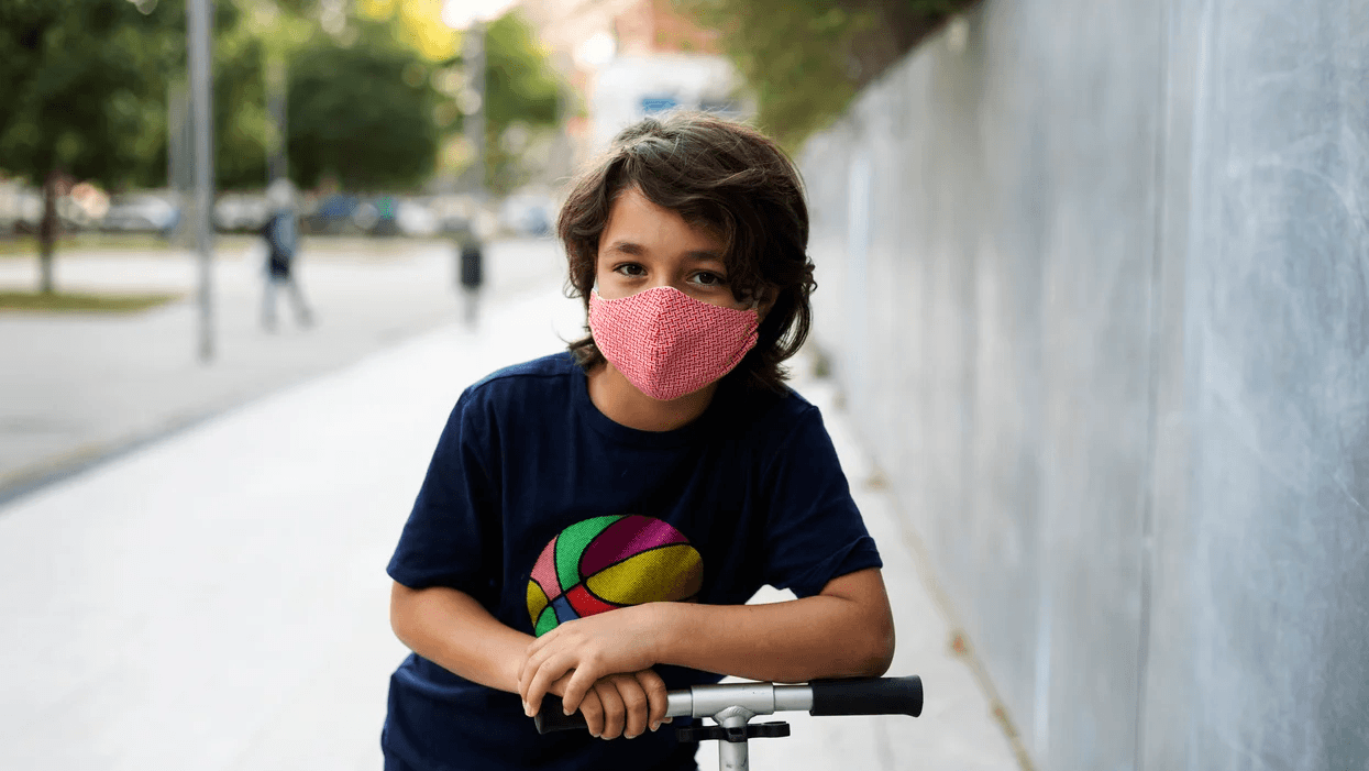 All your questions about kids & face masks, answered child wearing face mask on a scooter