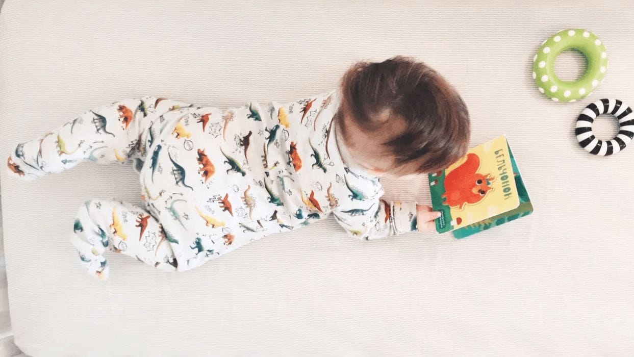 30+ essential board books for baby’s first year baby laying on belly looking at one of the best board books for babies
