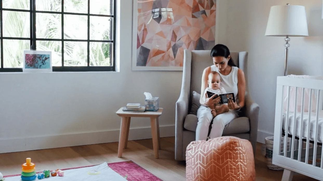 The best books for babies: 12+ Picks for every age mom in nursery with infant on her lap, reading one of the best books for babies
