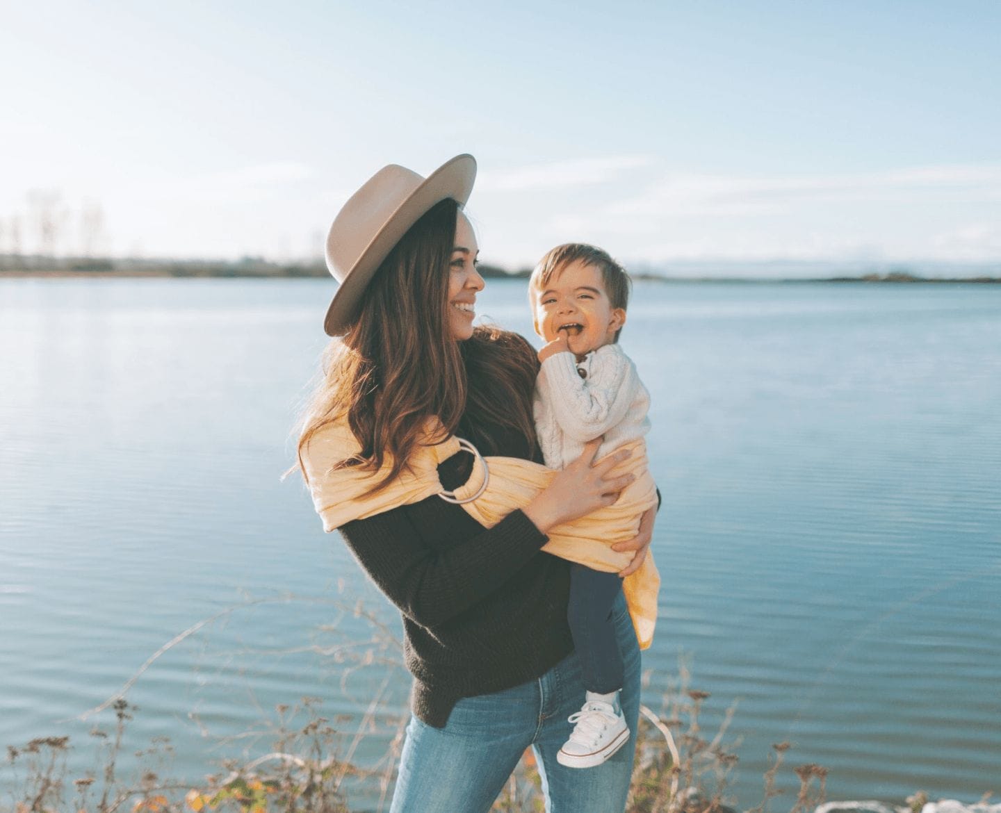 I felt lost as a new mother— babywearing helped me find myself again mom wearing baby on her hip standing in front of a lake