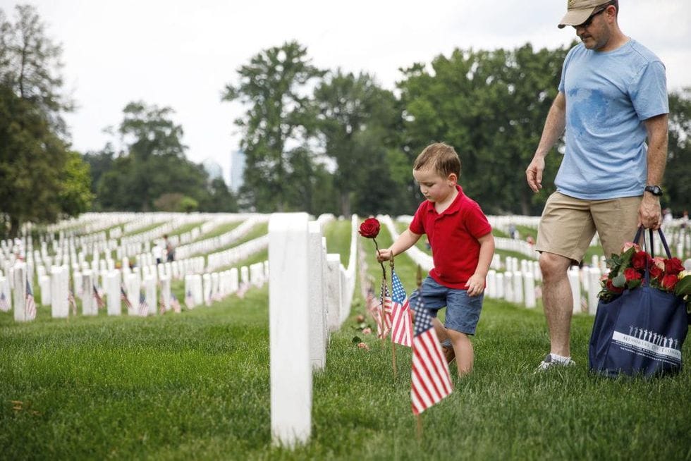 Child-placing-rose-on-tombstone-at-Arlington-National-Cemetery.