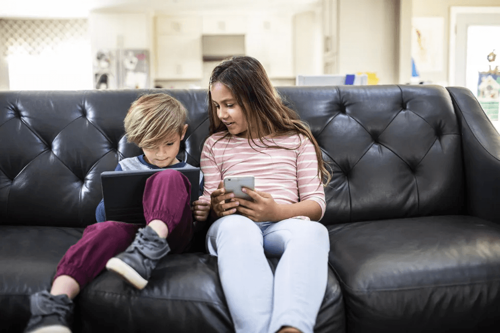 Even 5 hours of screen time per day is OK for school-aged kids, says new study kids-using-tablet-and-phone-on-sofa