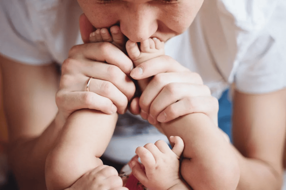 3-month-old baby milestones mom kissing baby's toes in celebration of 3 month milestones