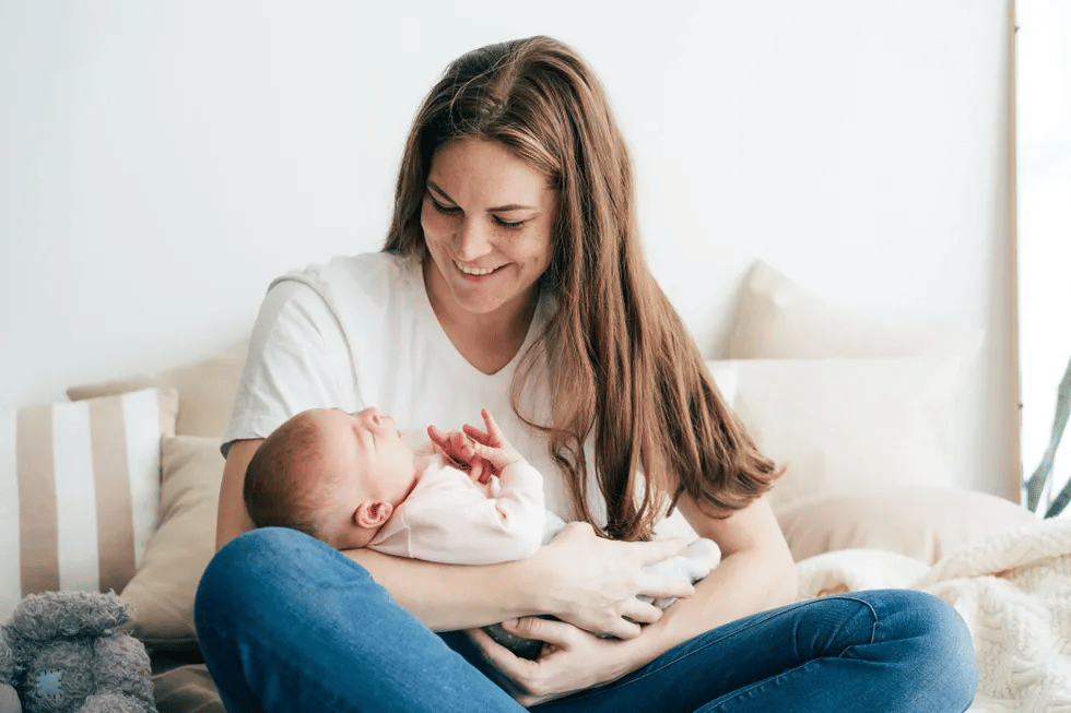 10 essential ways new moms can support their mental health new mom holding her newborn on the couch