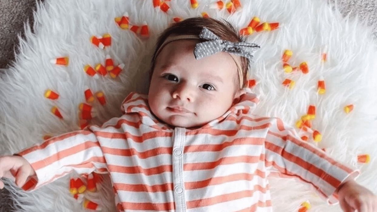 6 reasons October babies are special baby in orange stripes surrounded by fake leaves - october babies
