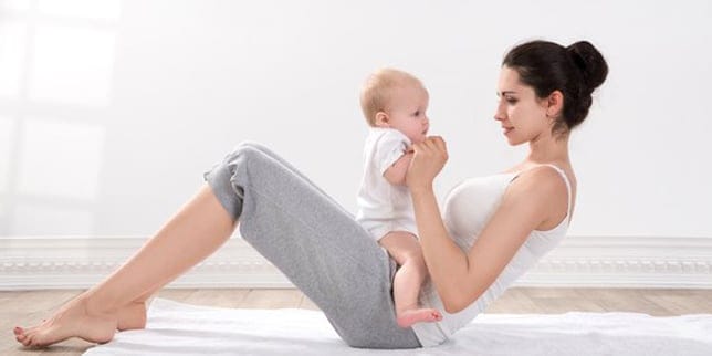 Do I Have Diastasis Recti? mother leaning back with baby on her belly, wondering if she has diastasis recti