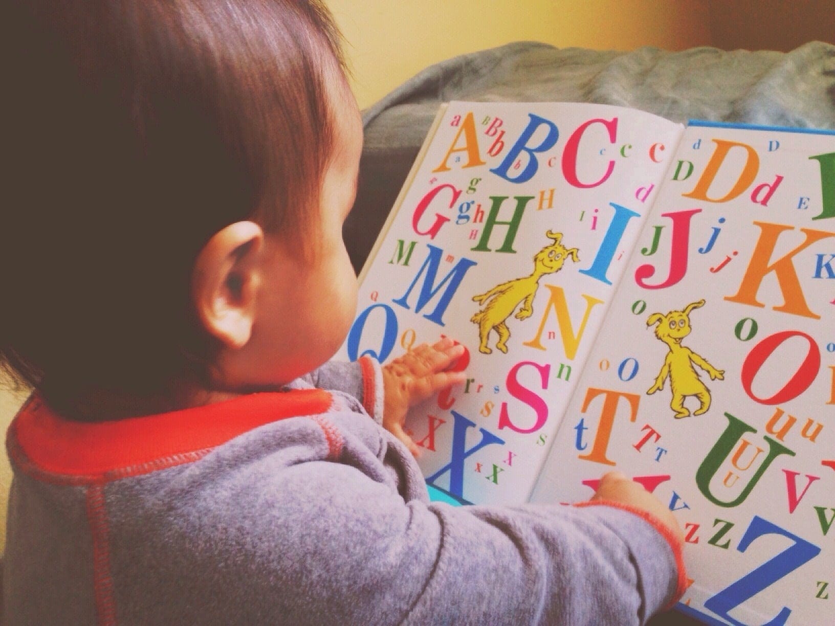 5 activities to support bilingualism in early childhood baby looking at a book with colorful letters, an activity that supports bilingualism in early childhood