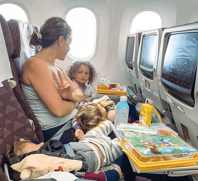 To the parents worrying about taking your kids on a flight—you can do this mom holding a baby and sitting next to a toddler on a plane