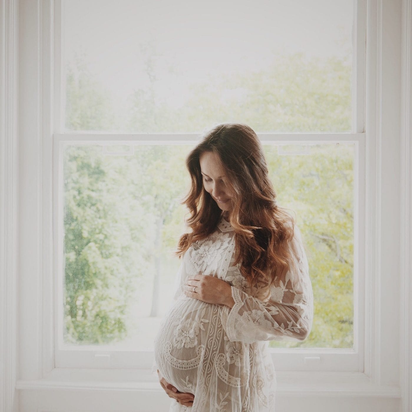5 ways to take baby’s name for a test drive mom standing in front of a window holding her belly