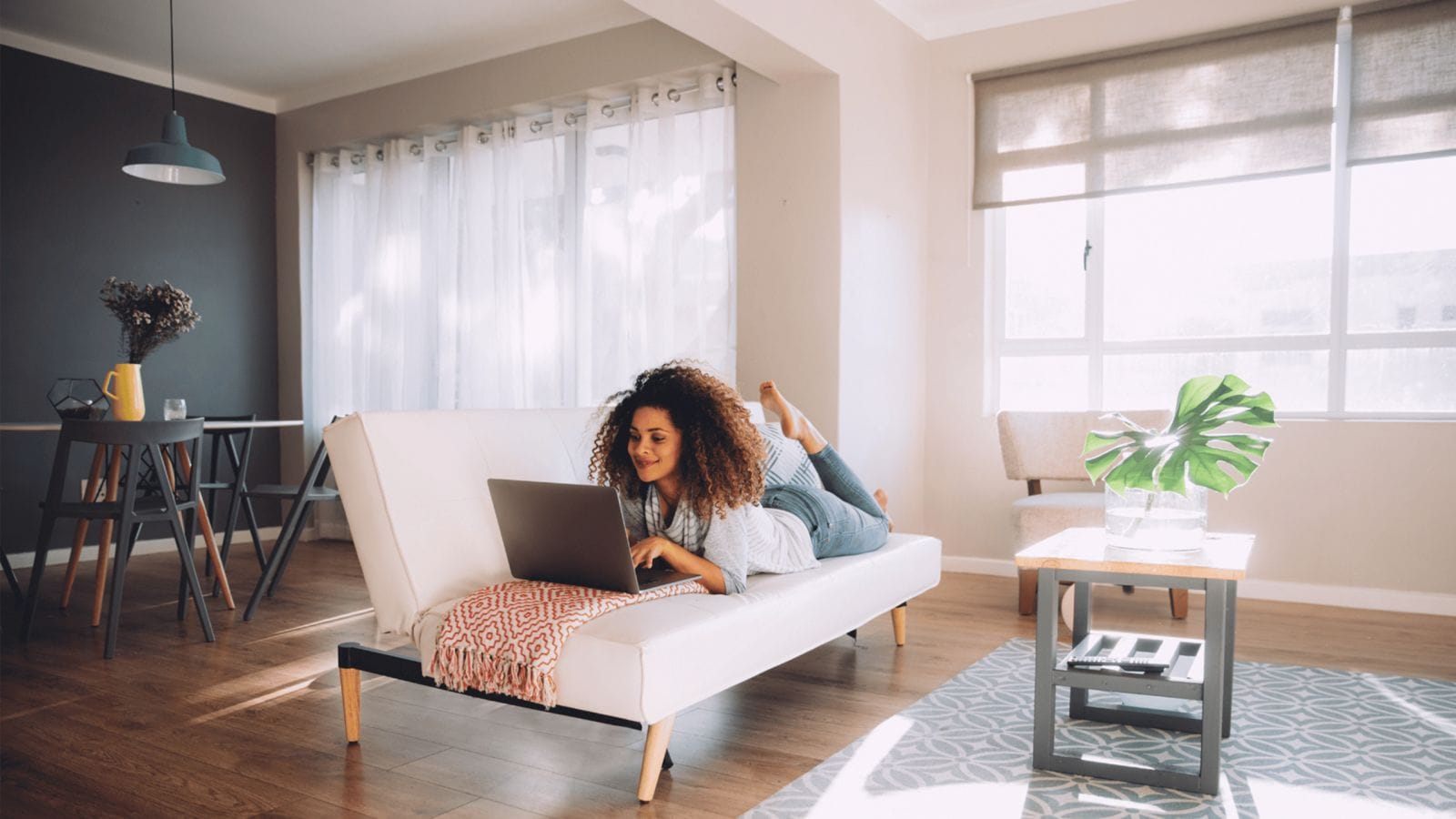 9 ways to reduce your household carbon footprint right now woman laying on the couch working on a computer