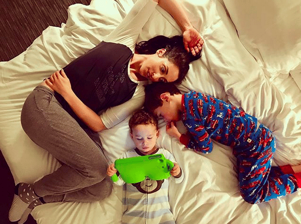 “Workin’ Moms” star shares how she’s getting through quarantine with kids Catherine Reitman sitting with kids on a bed