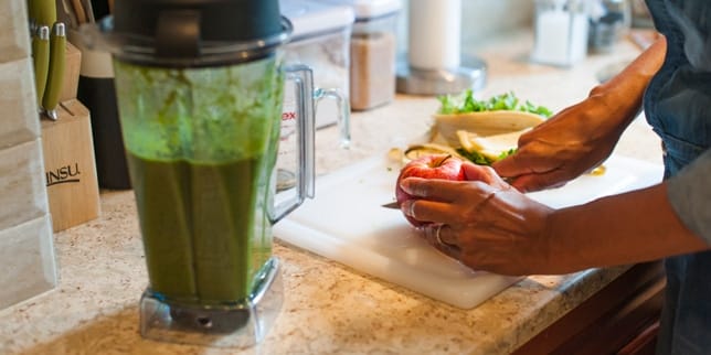 5 fall vegetables for a healthy pregnancy smoothie next to a woman chopping vegetables