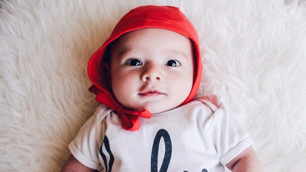 5 steps to prepare your budget for a baby before she’s born baby wearing a red cap