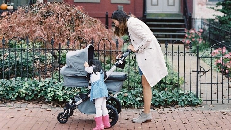 Bringing baby to day care? 8 ways to ease the transition & feel good about your choice mom walking with daughter and baby in a stroller, preparing how to transition baby to daycare