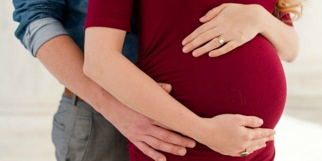 My baby was misdiagnosed with Trisomy 18 man and woman embracing her pregnant belly