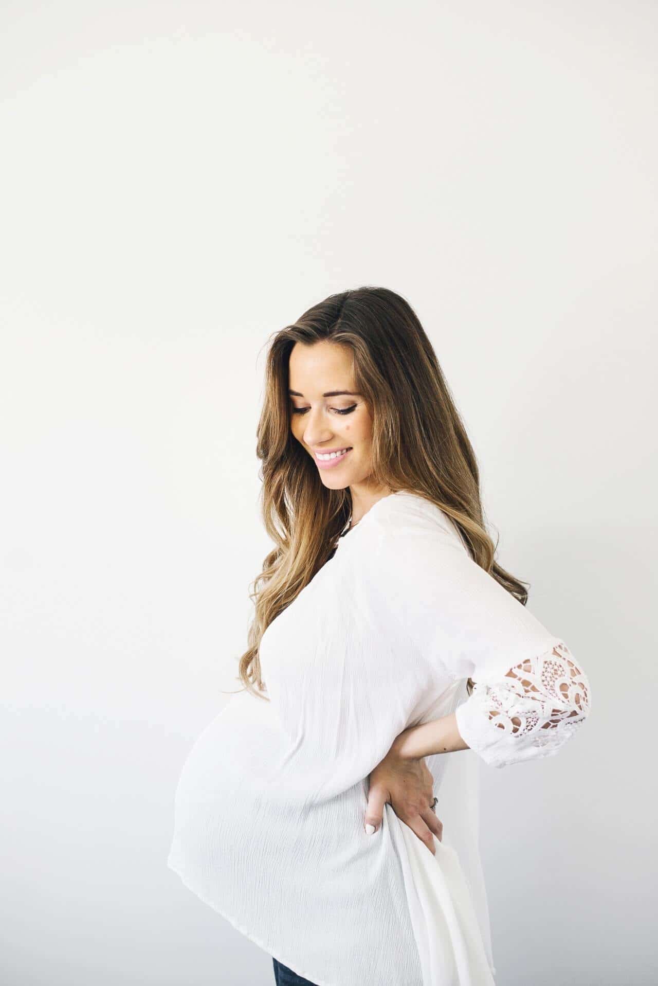 8 things to do now to prepare for your C-section woman holding her pregnant belly as she takes steps on how to prepare for a c section
