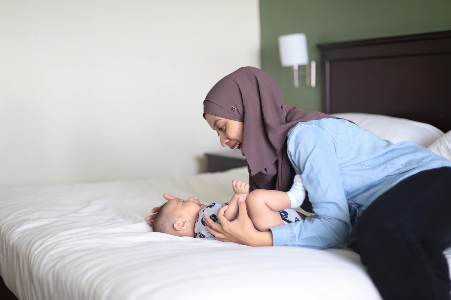 Living in the moment: 7 ways to enjoy motherhood more by being present mom playing with baby on a bed