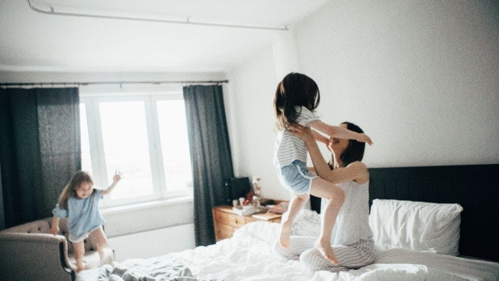The day I stopped saying ‘hurry up’ and started enjoying motherhood mom playing with two toddlers jumping on a bed