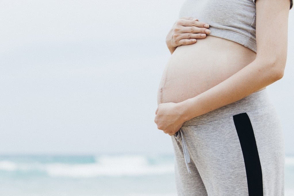 Wondering how to avoid a c-section? New study says to get moving during pregnancy woman cradling her pregnant belly, wondering how to avoid a c section