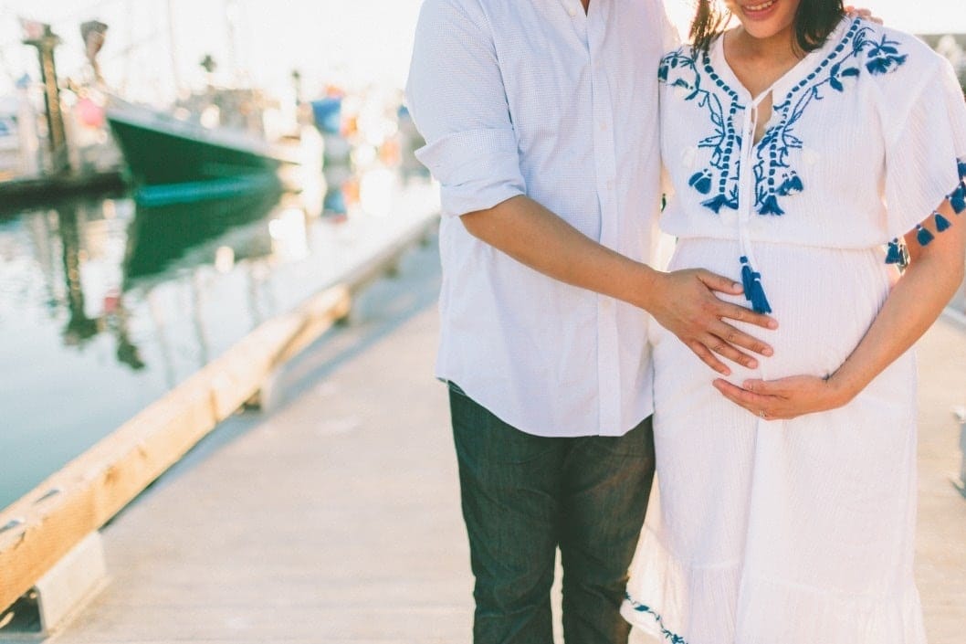 Having this one discussion before baby arrives can help your relationship couple walking together on boardwalk