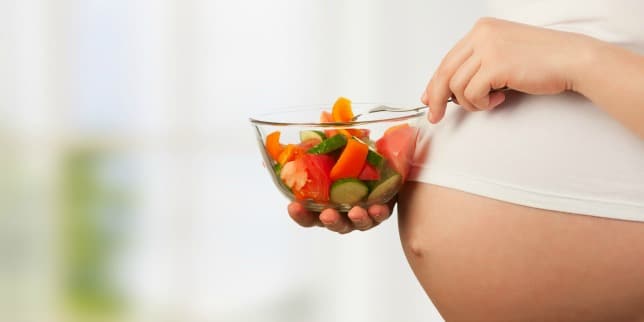 What you need to know about eating during labor pregnant person holding bowl of fruit