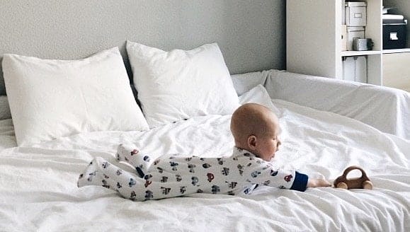 Montessori milestones: 4 developmental milestones you won’t find in baby books baby reaching for a toy, displaying the montessori milestone of problem-solving skills