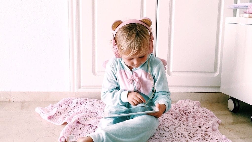 From one mama of an anxious child to another—here’s how we cope little girl sitting on bed with ipad