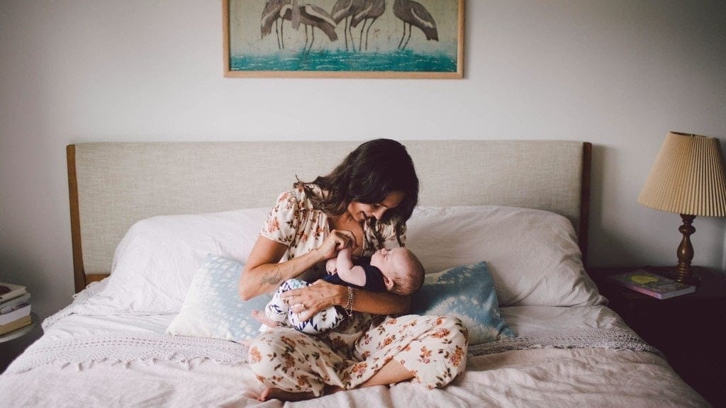 The good news about infant attachment—you’re probably already doing it mom holding newborn baby on bed, fostering infant attachment