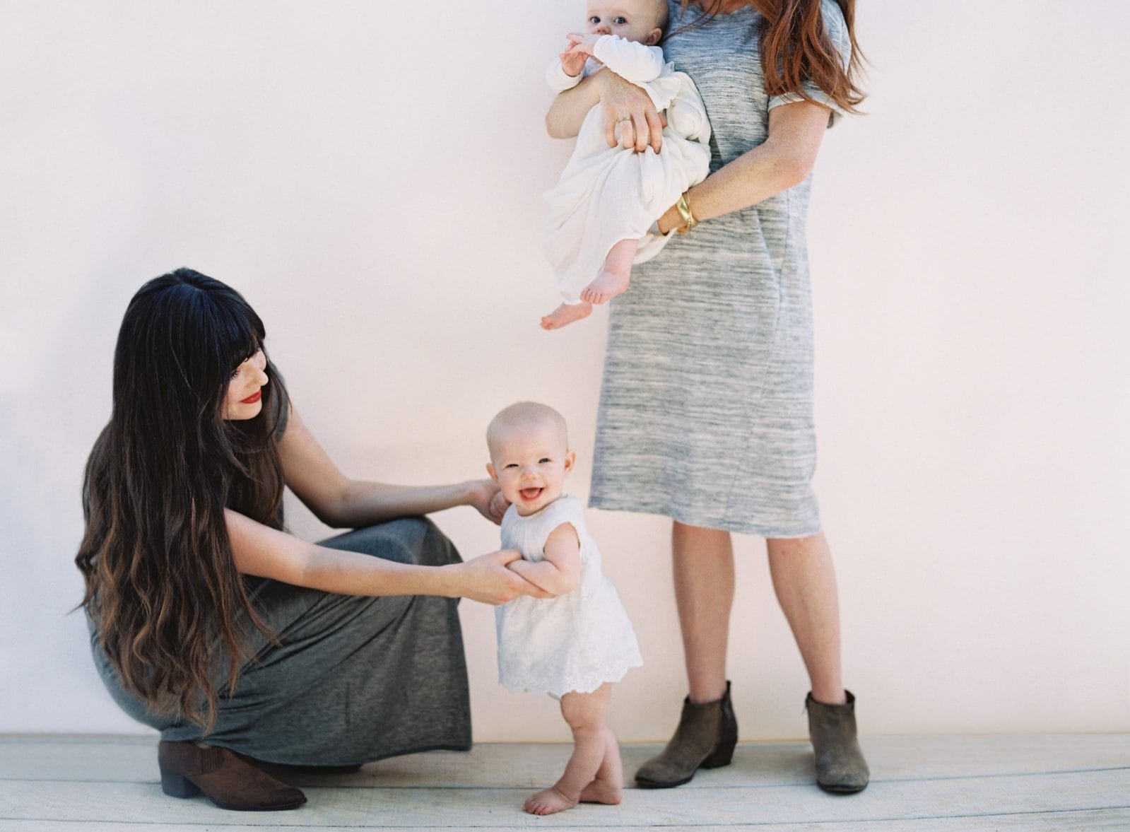 A ‘thank you’ to the mom friends who love my children as their own one mom holding a baby while another mom helps a toddler stand