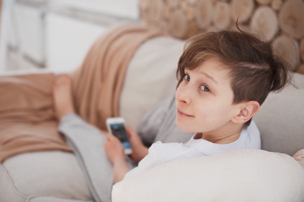 Facebook’s new Messenger Kids app aims to give moms peace of mind tween sitting on couch with phone
