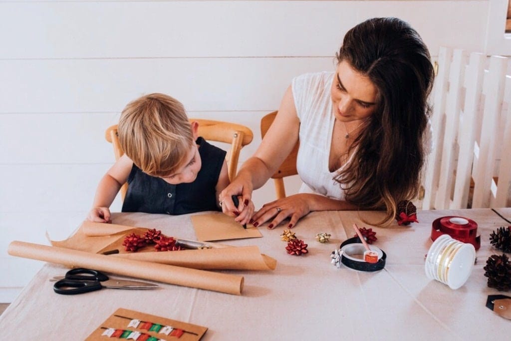 I want to raise my kids to love giving as much as receiving child helping mom write holiday cards- giving back to the community
