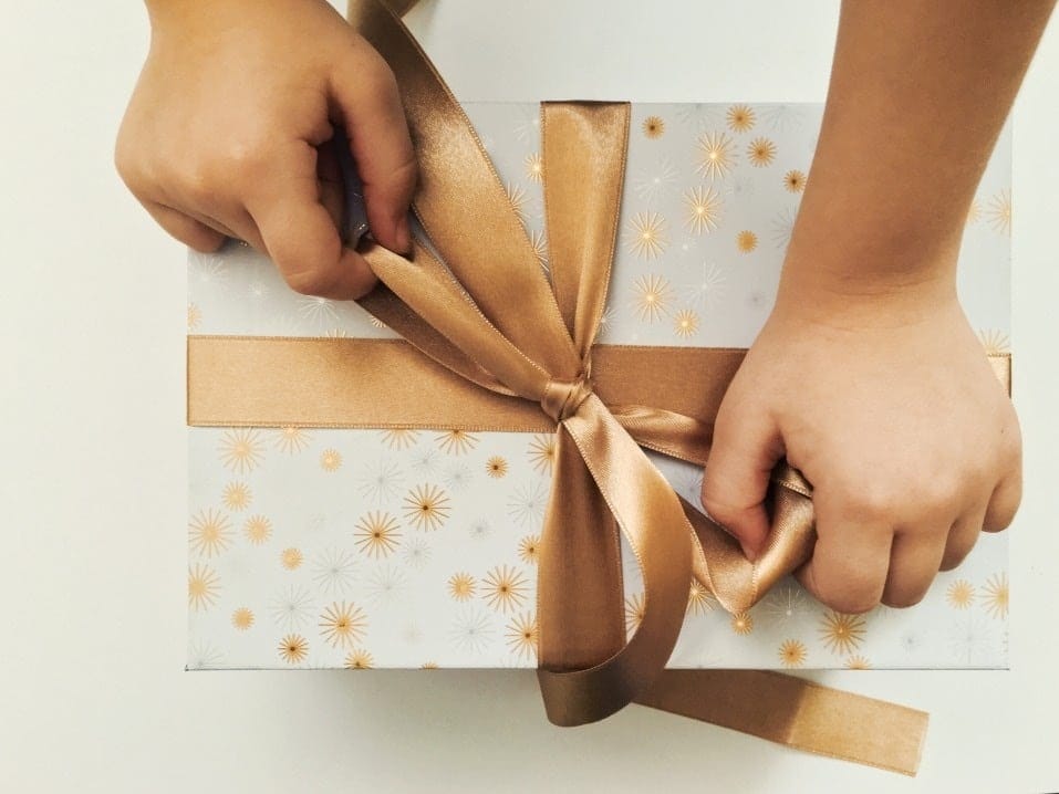 Last-minute shoppers: Amazon’s offering free same-day shipping for the holidays little child hands wrapping a bow on a present