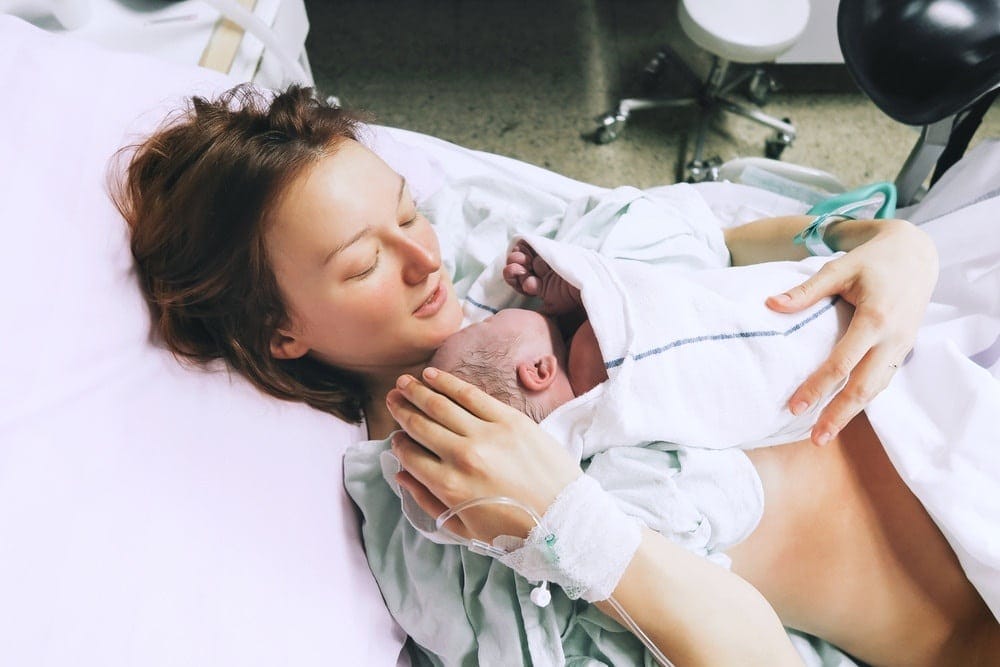 What is a lotus birth? Here are the basics, mama lotus birth: woman holding newborn in hospital