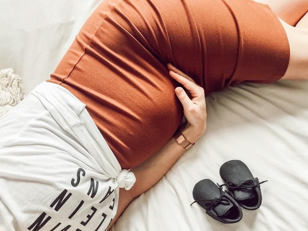 Dear mama-to-be, I envy you pregnant woman holding belly laying on the bed