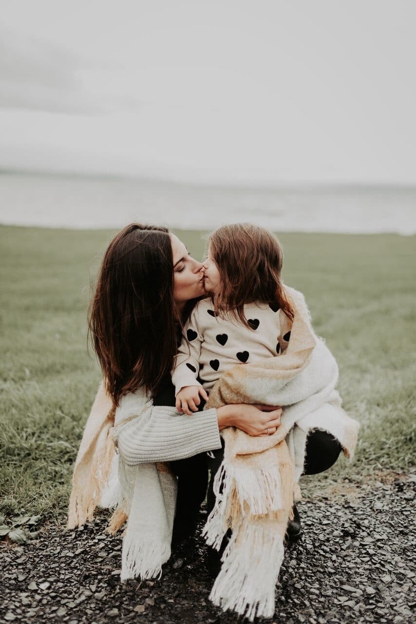 Your first day of school is a first for me, too mom kissing daughter on first day of kindergarten