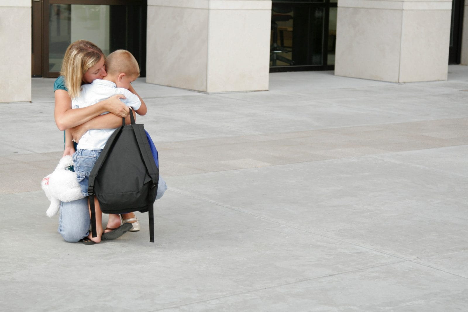 9 tips to ease your child’s anxiety—and your own!—about going back to school mom hugging son outside of school