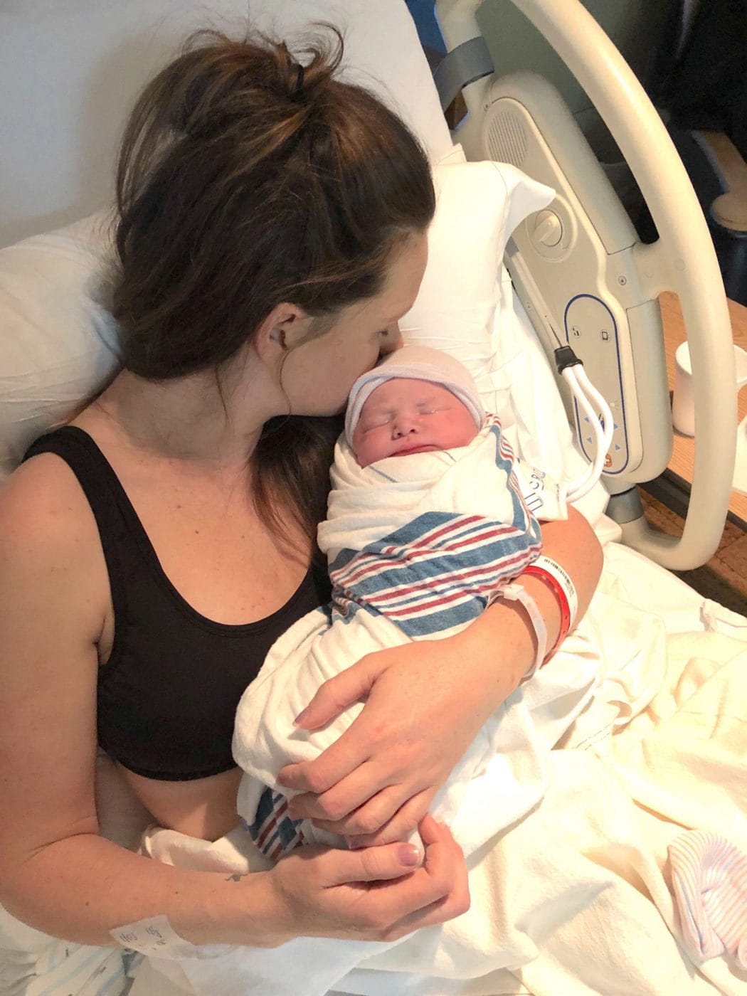 My birth story: I was induced at 39 weeks mom kissing newborn baby in the hospital after getting induced at 39 weeks