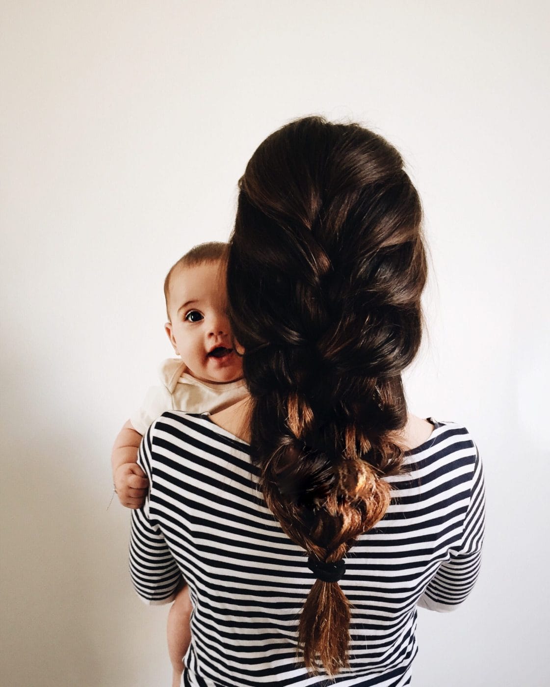 These are the best hairstyles for mamas who have no time mom with a large braid holding a baby- hairstyles for moms