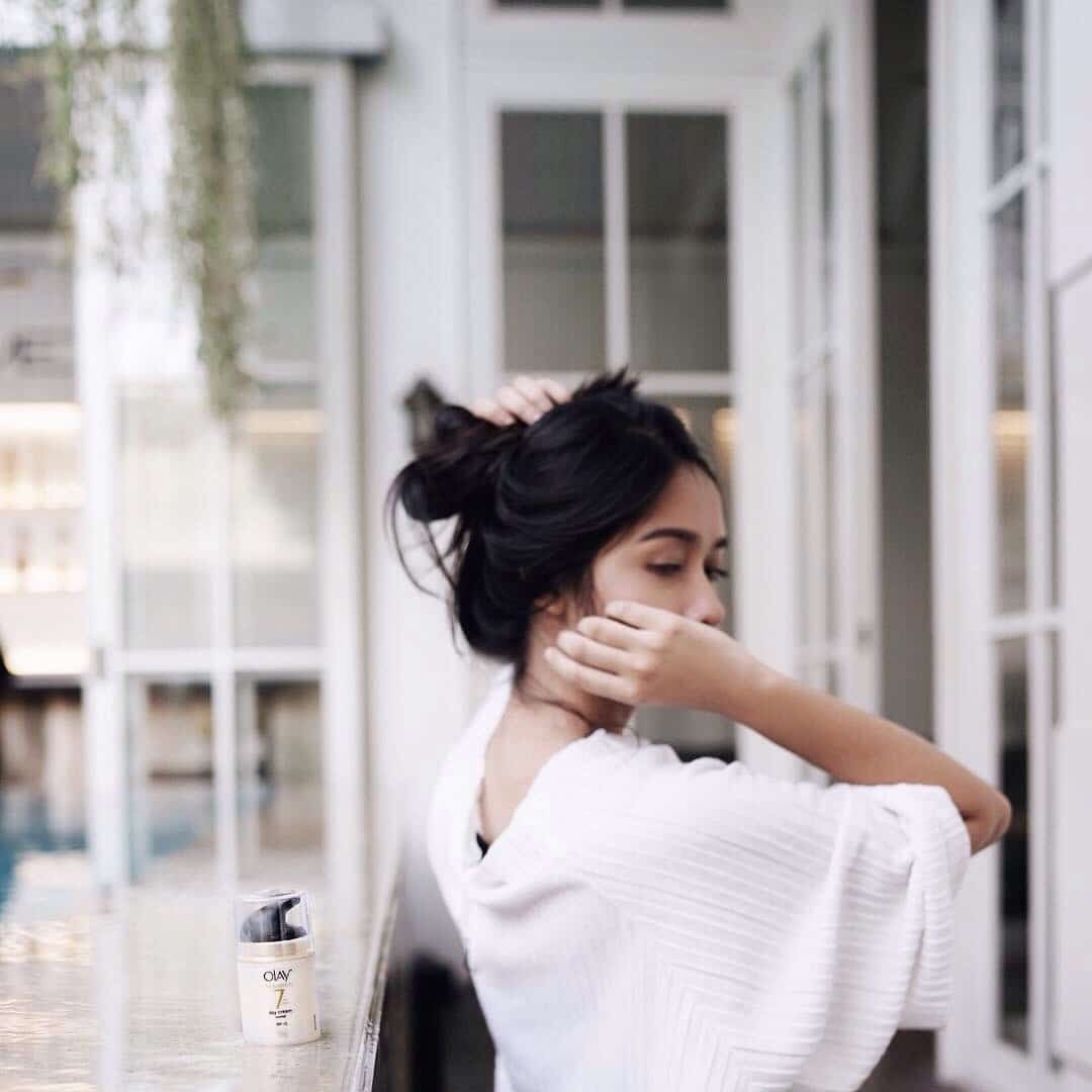 How to combat postpartum hair loss, mama (and products that really help!) woman putting her hair in a bun