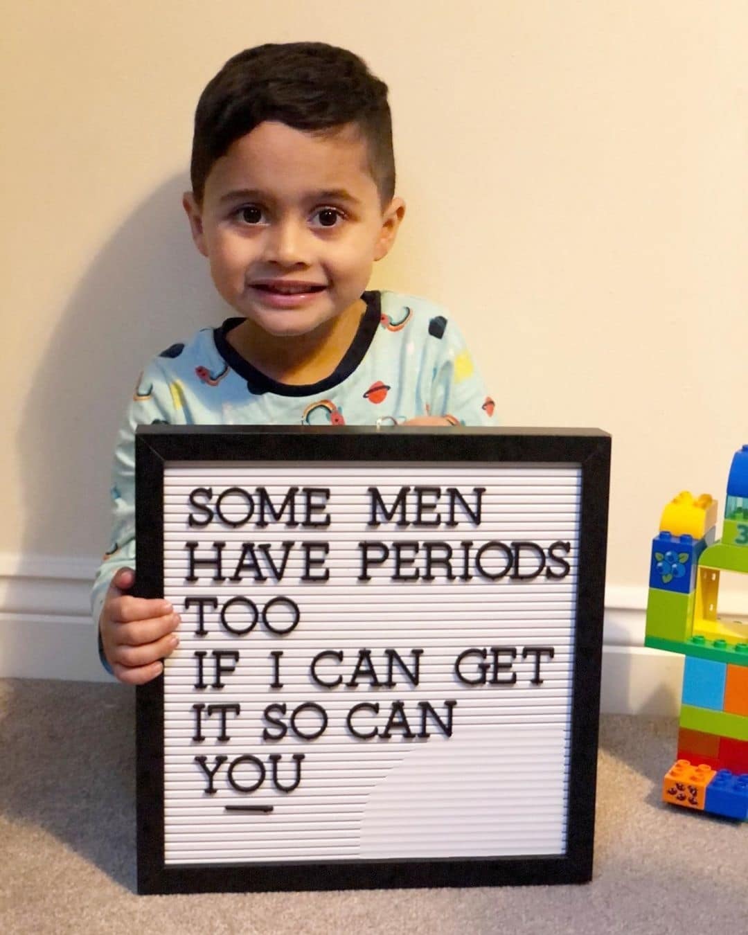 This powerful photo of a 4-year-old promotes inclusivity little boy holding a letterboard sign