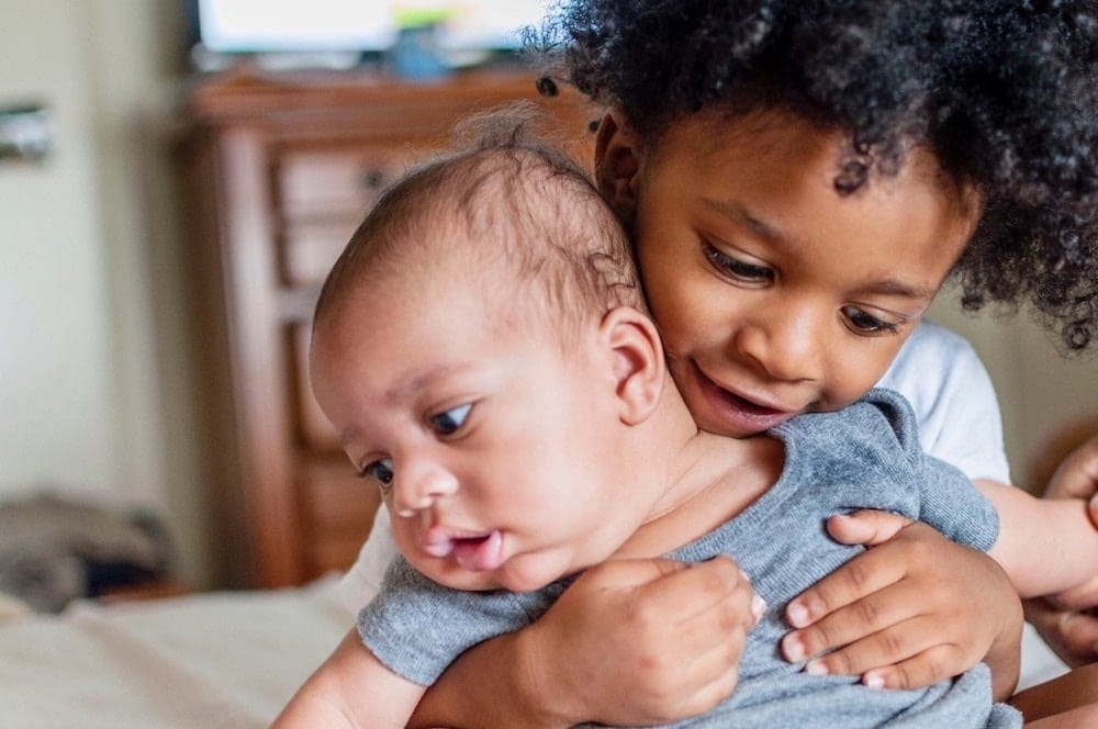 It’s science: Having younger siblings helps you become a more caring person older sibling holding baby