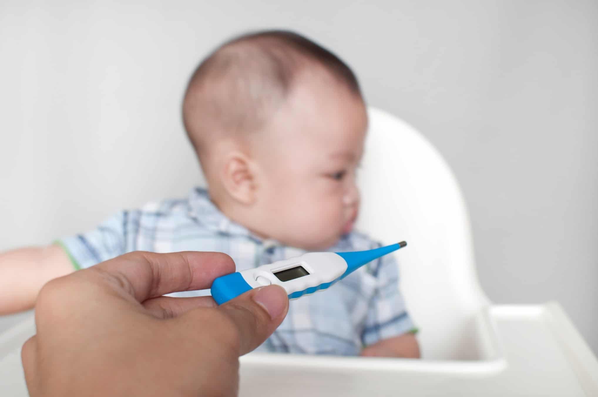How do I get my child’s fever down?—and when to call a doctor thermometer in front of a baby