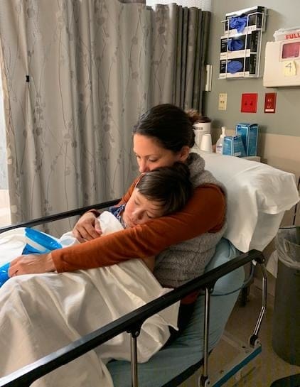 This viral photo proves that moms are *always* working mom working in a hospital bed holding her son