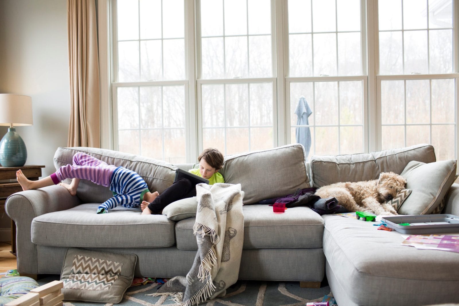 5 ways parents can make space (physically and mentally) in the new year one child on ipad, one child playing on couch, & dog sleeping on couch- how to declutter your life